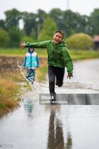Стокове фото Щасливий Сміється Хлопчик Біжить По Калюжі Води Під Дощем — Завантажте зображення зараз - iStock